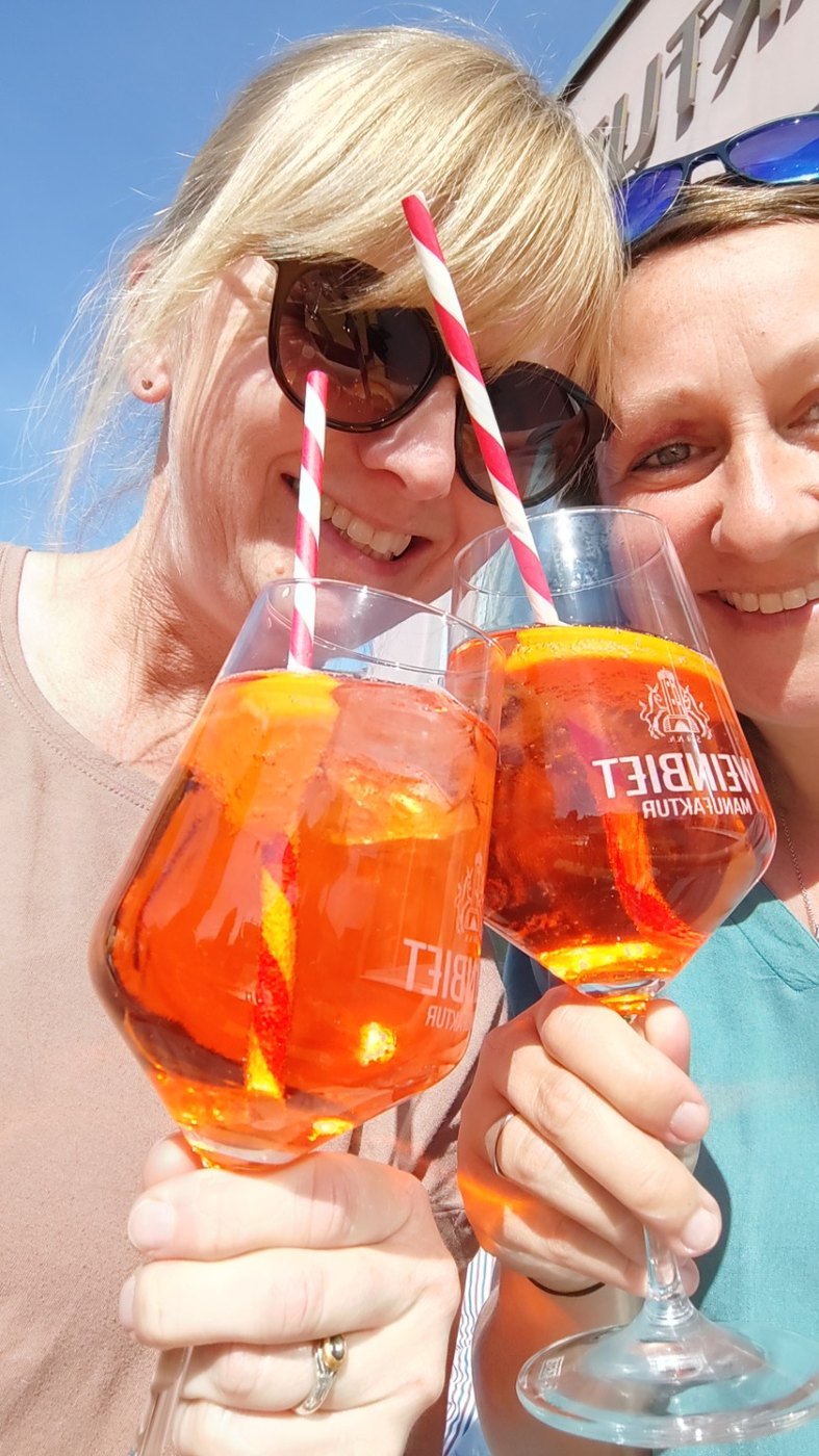 Zwei Freundinnen stoßen mit Aperol an